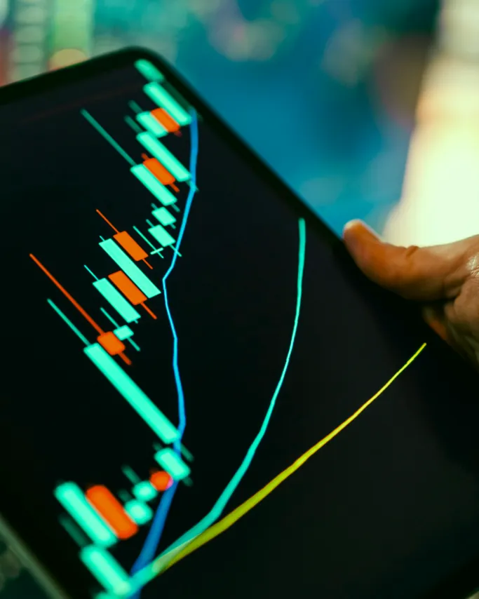 Hand holding a tablet that displays a financial chart